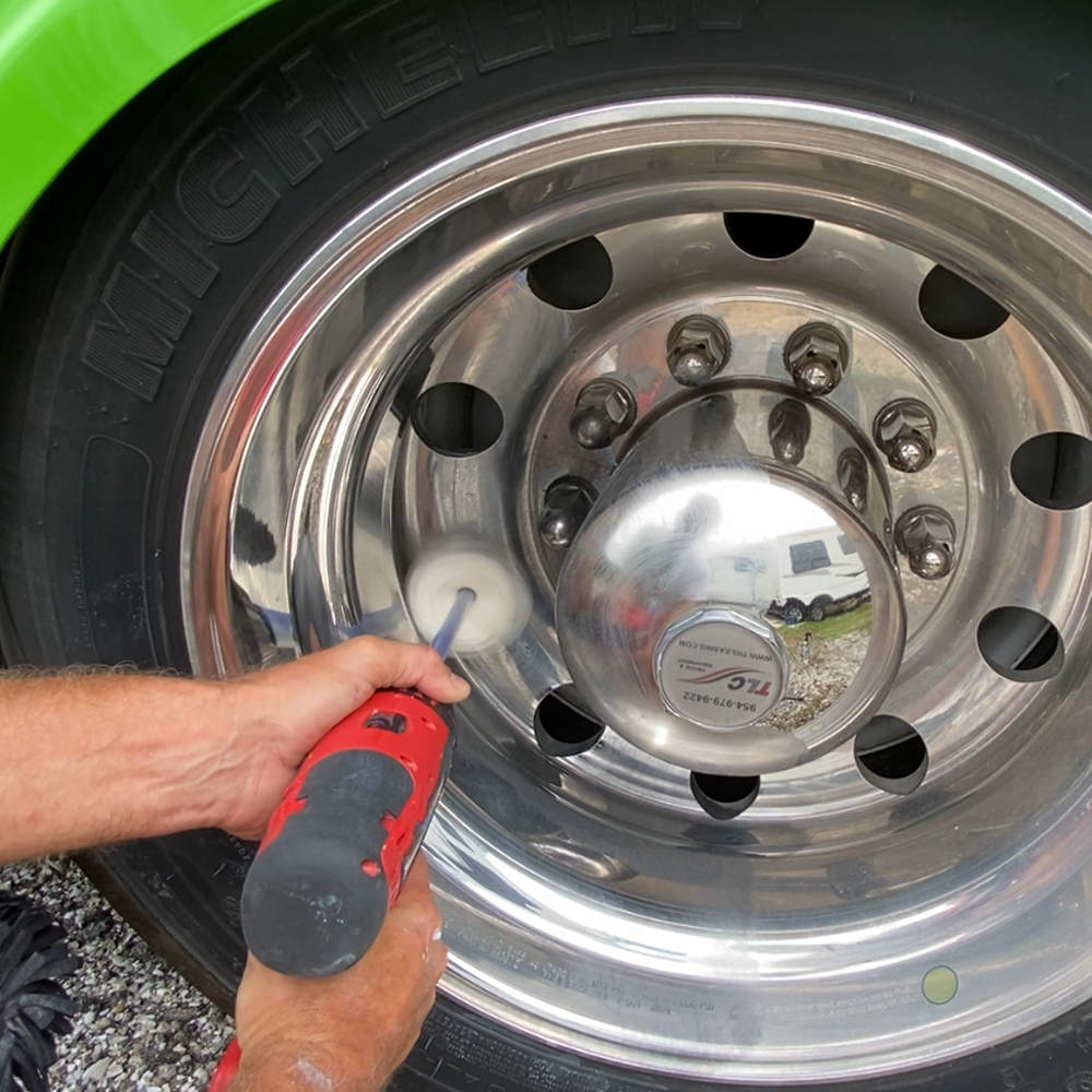 A person uses a mini Flitz buffball to polish aluminum car wheels.