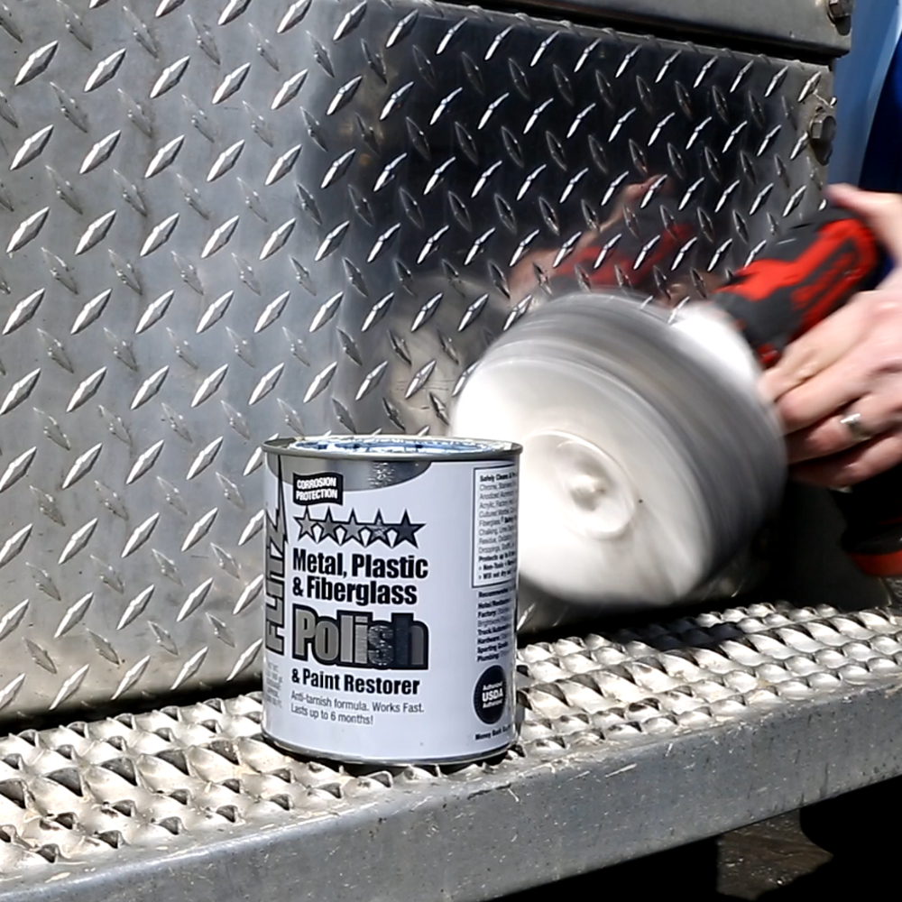 A person uses a Flitz buffball and a can of Flitz polish past to polish a stainless steel truck bed